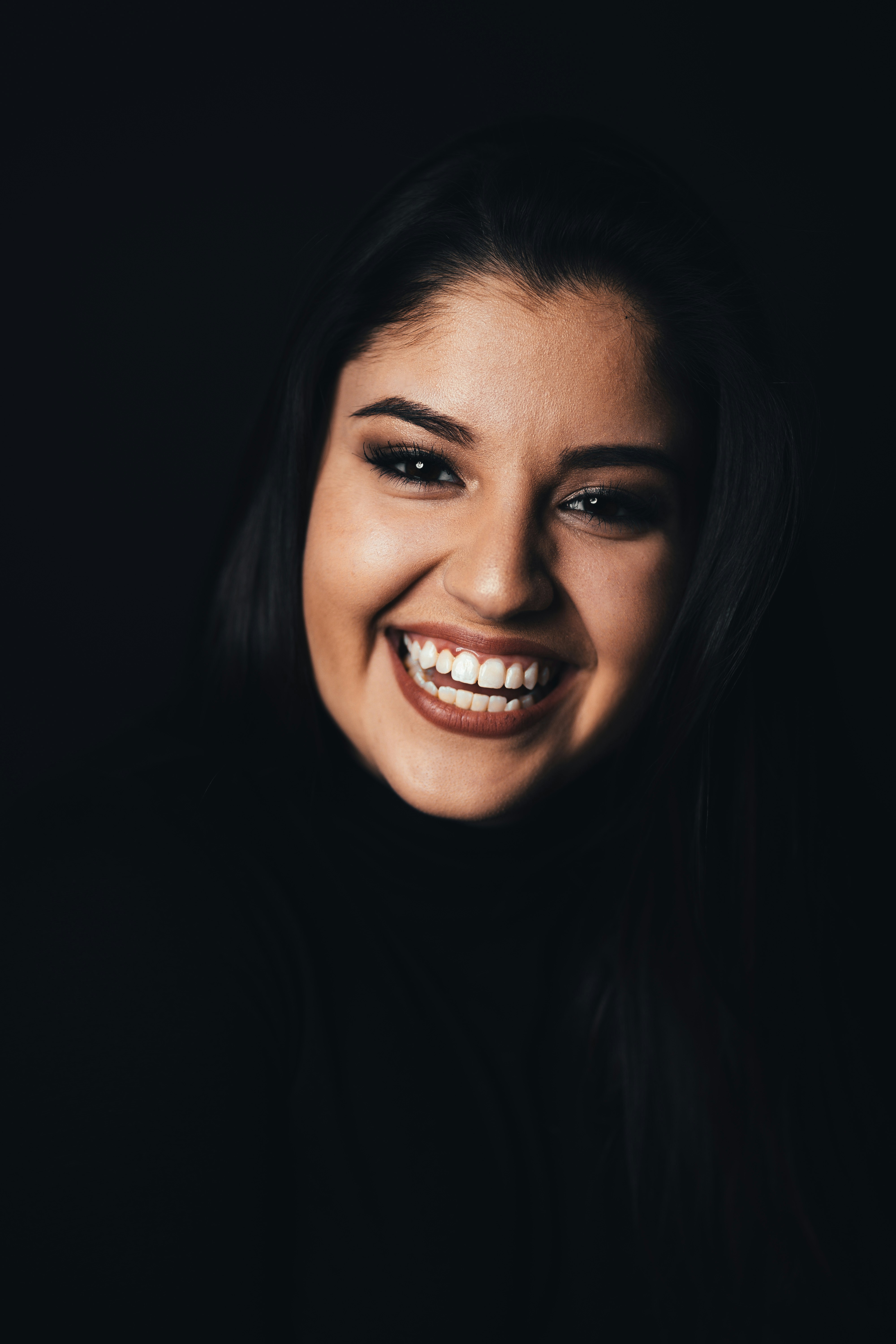 A young woman smiling warmly, eyes full of hope