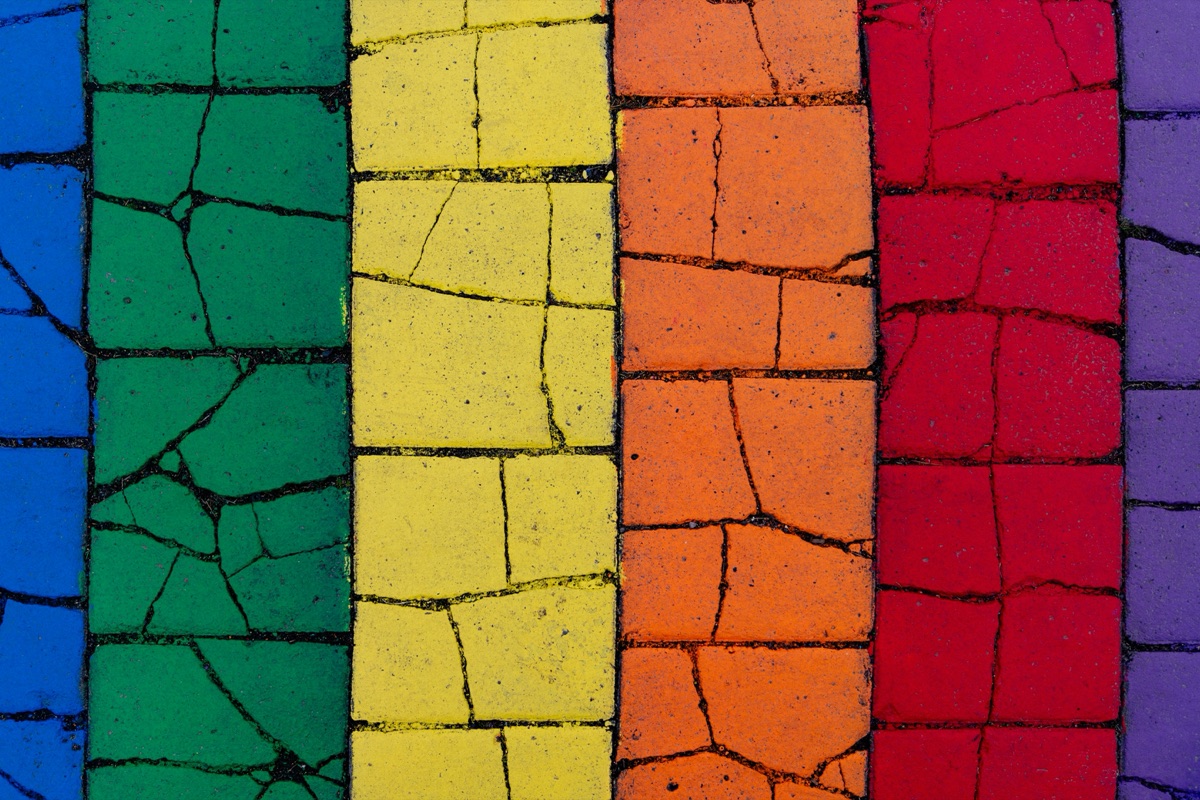Rainbow stripes on a cracked surface, symbolising LGBTQ+ identity and resilience